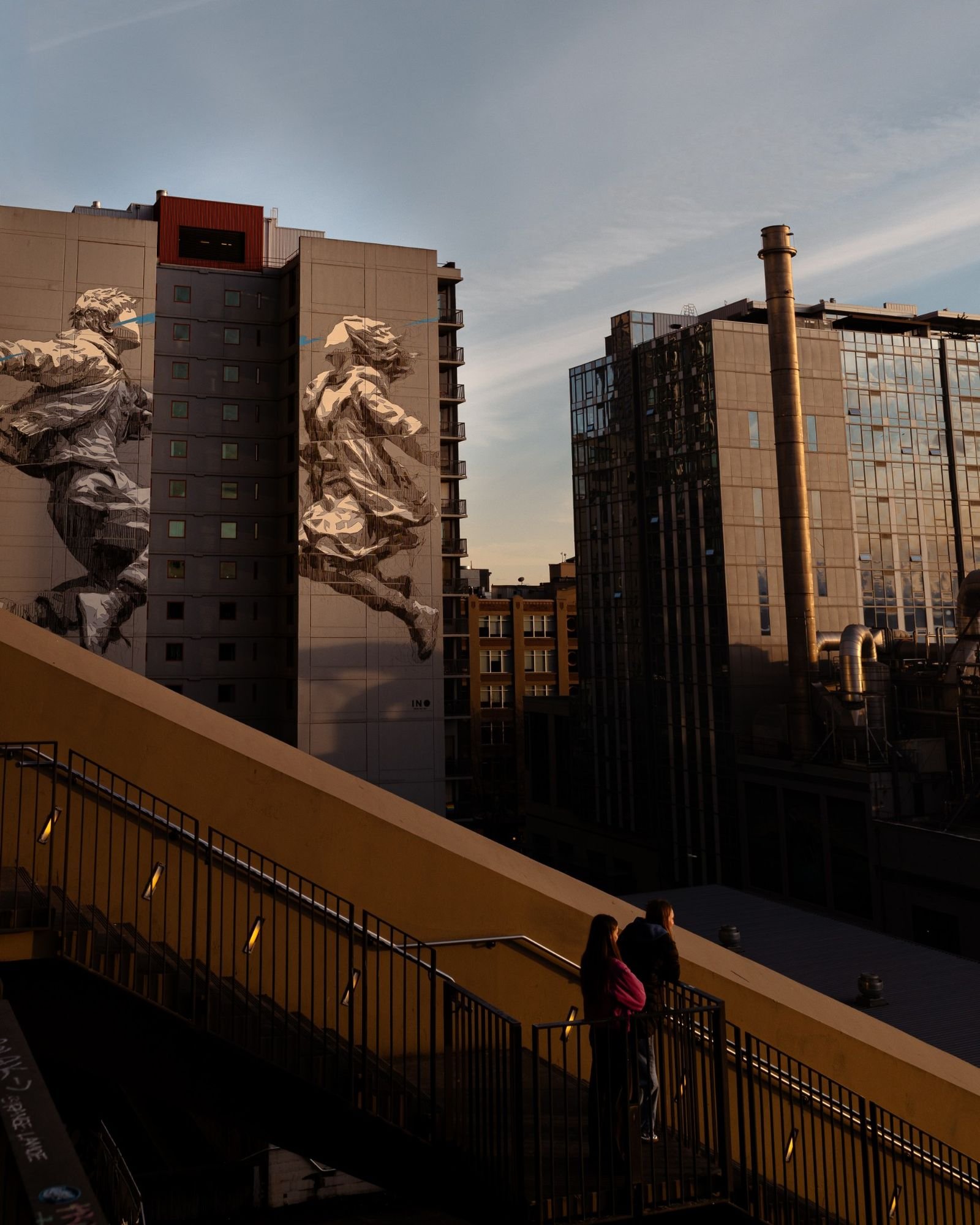 buildings at sunset with two murals of people trying to kiss